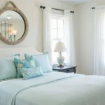 Calm bedroom with coastal wall decor and light blue bedding.