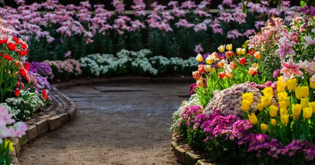 A vibrant spring garden with colorful flowers, lush green grass, and a sunny sky.